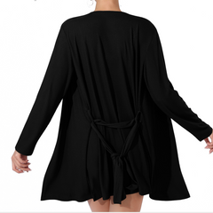 Black dress with long sleeves and a tie waist worn by a model on a white background.